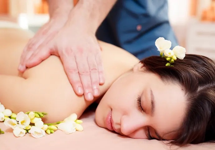 Massage therapist applying gentle pressure to client’s back in quiet treatment room