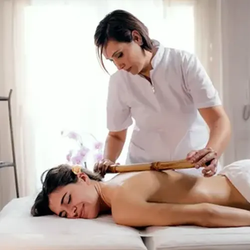 Set of wooden massage tools arranged neatly beside folded towels and candle